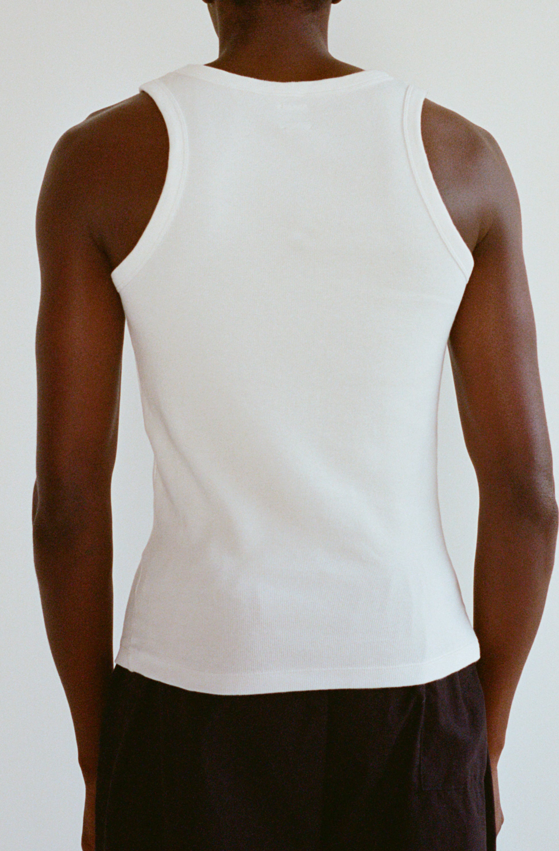 Le débardeur large blanc pour homme et femme en coton côtelé bio OMEAR, porté homme de dos